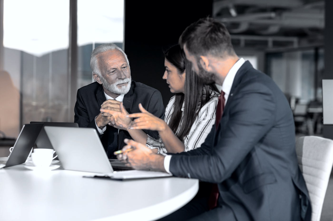 Three executives in discussion across a boardroom table